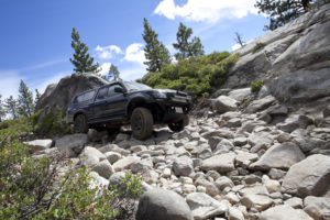 blue 4x4 truck with camper cover driving over boulders Wizard Transmission Denver